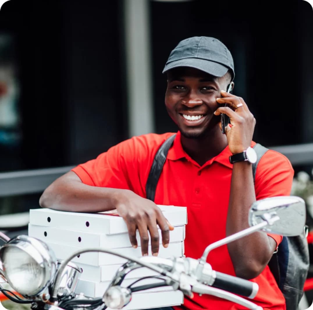Un livreur Restau Proche au téléphone, ses commandes prêtes à partir.